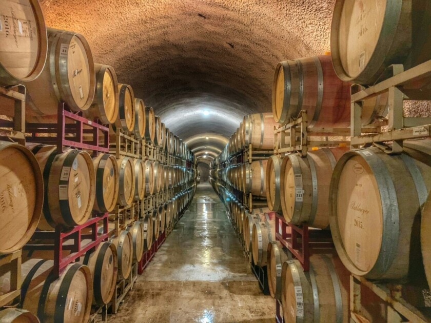 Wine barrels line the walls in long cellar