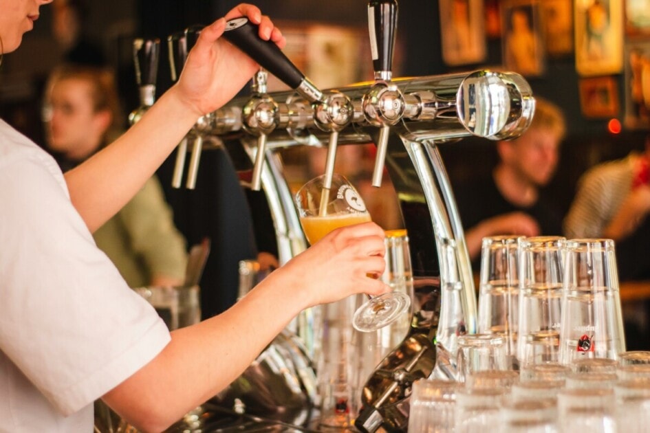 A bartender pours a pint of beer