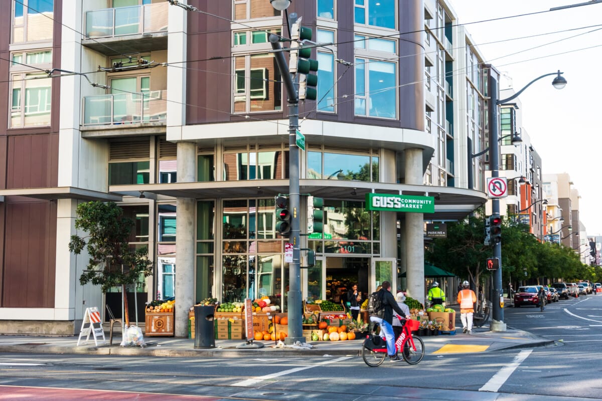 someone biking in front of Gus's community market in the mission bay neighborhood of san francisco