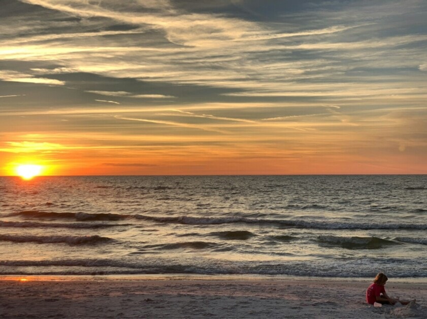 Girl playing in the sand at St Pete Beach at sunset