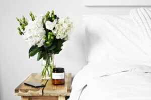 A candle next to a bed and flowers