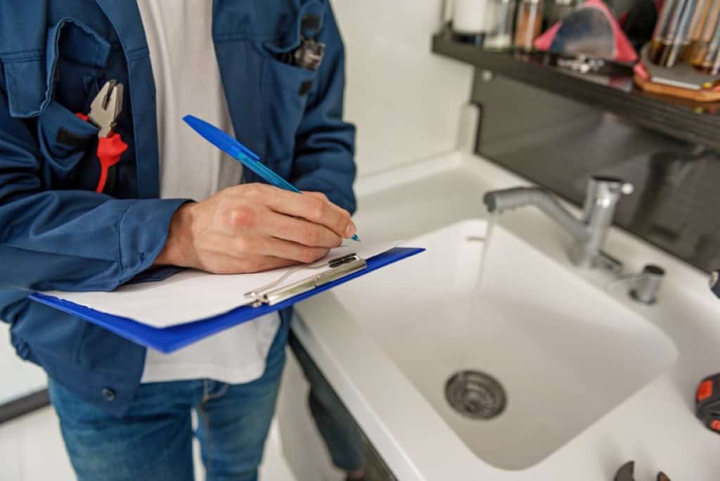a home inspector looking at the plumbing in a home for sale