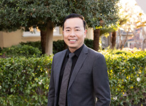Real estate agent Ted Chen standing outside in a suit and tie